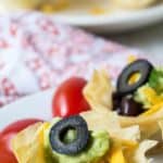 A mini taco cup topped with a sliced black olive.