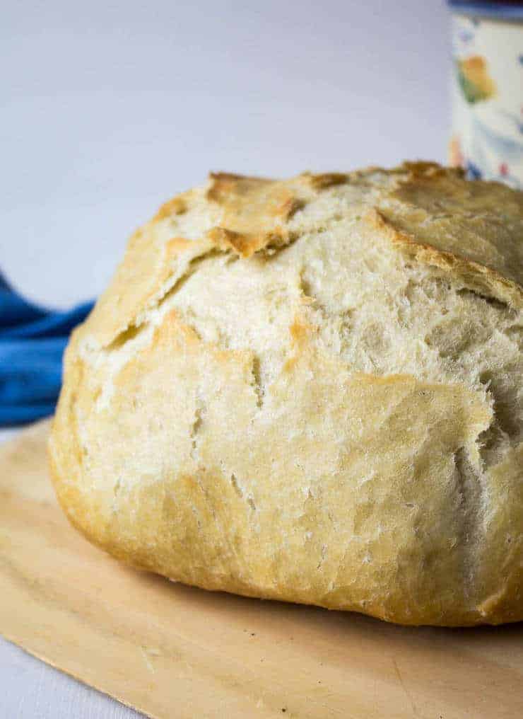 A round loaf of crusty bread on a wooden cutting board.