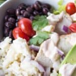 A salad topped with chicken, black beans, rice and avocadoes.