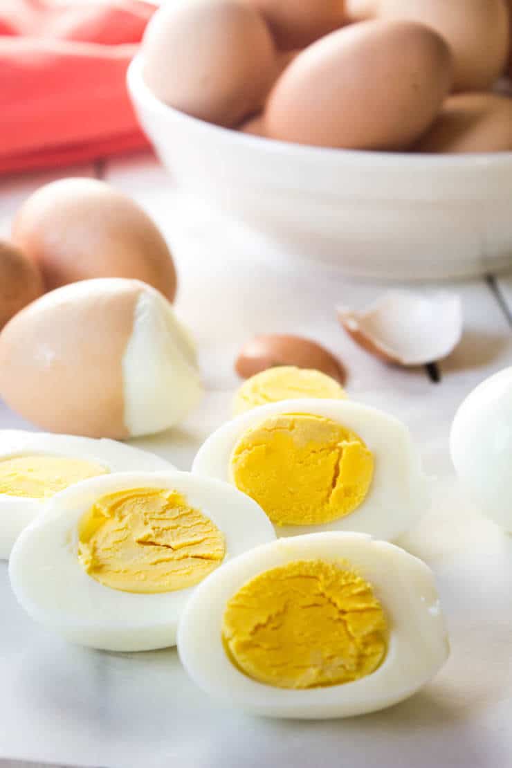 Hard boiled eggs sliced in half with more whole eggs in the background.