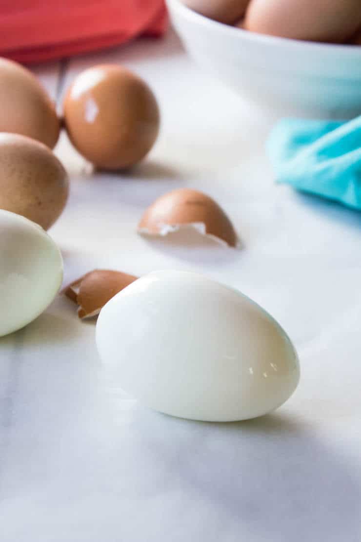 A peeled hard boiled egg with pieces of shell around the egg.