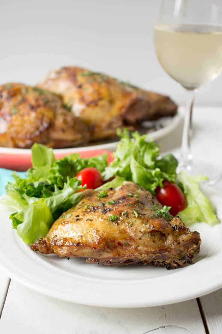 Chicken served on a white plate with a green salad. 