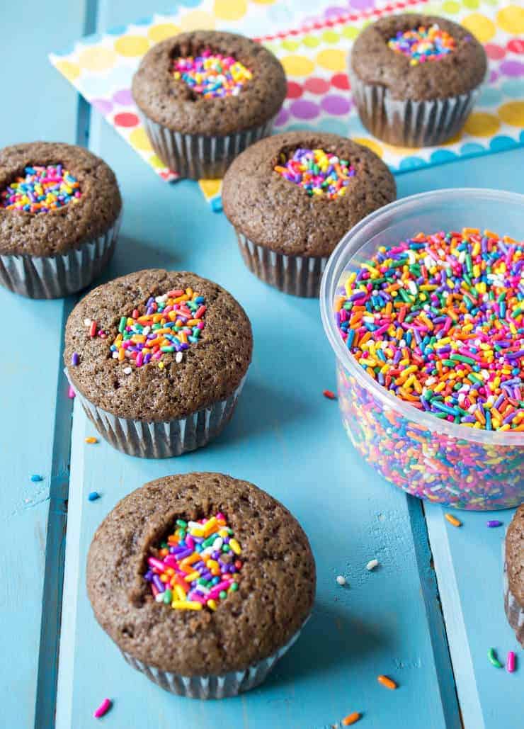 Cupcakes being filled with confetti sprinkles.