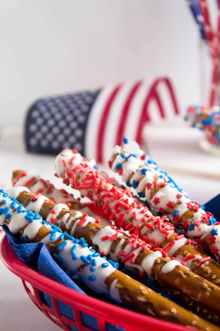 Chocolate covered pretzels with sprinkles in a red basket.