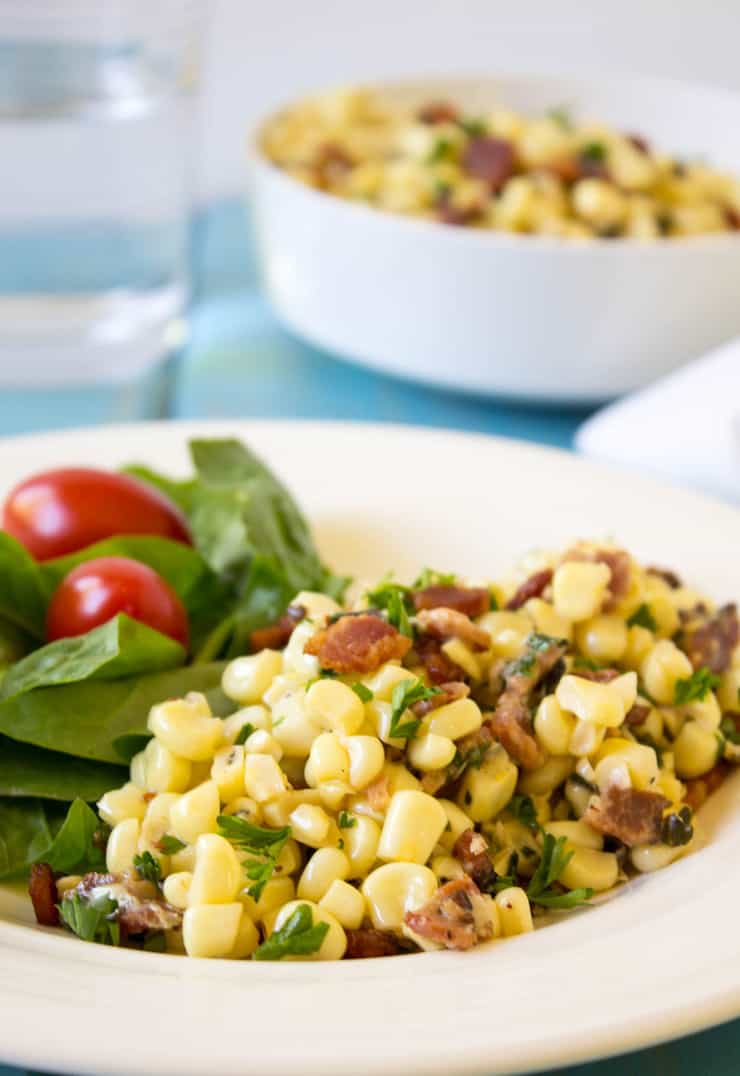 Corn with Bacon served with a side salad on a plate.