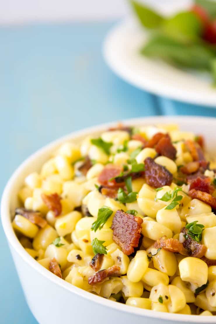 Sauteed Corn with Bacon topped with fresh herbs and chunks of bacon.