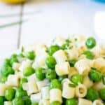 Small pasta and peas on a white plate.