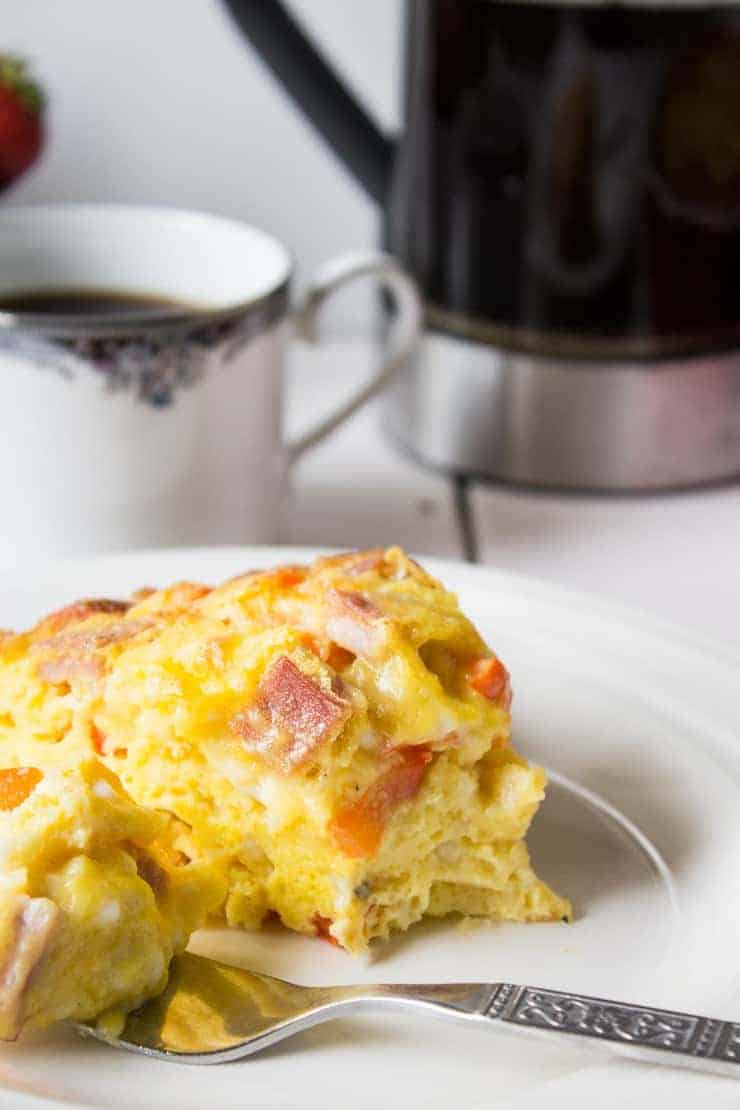 A slice of an egg casserole filled with peppers and ham.