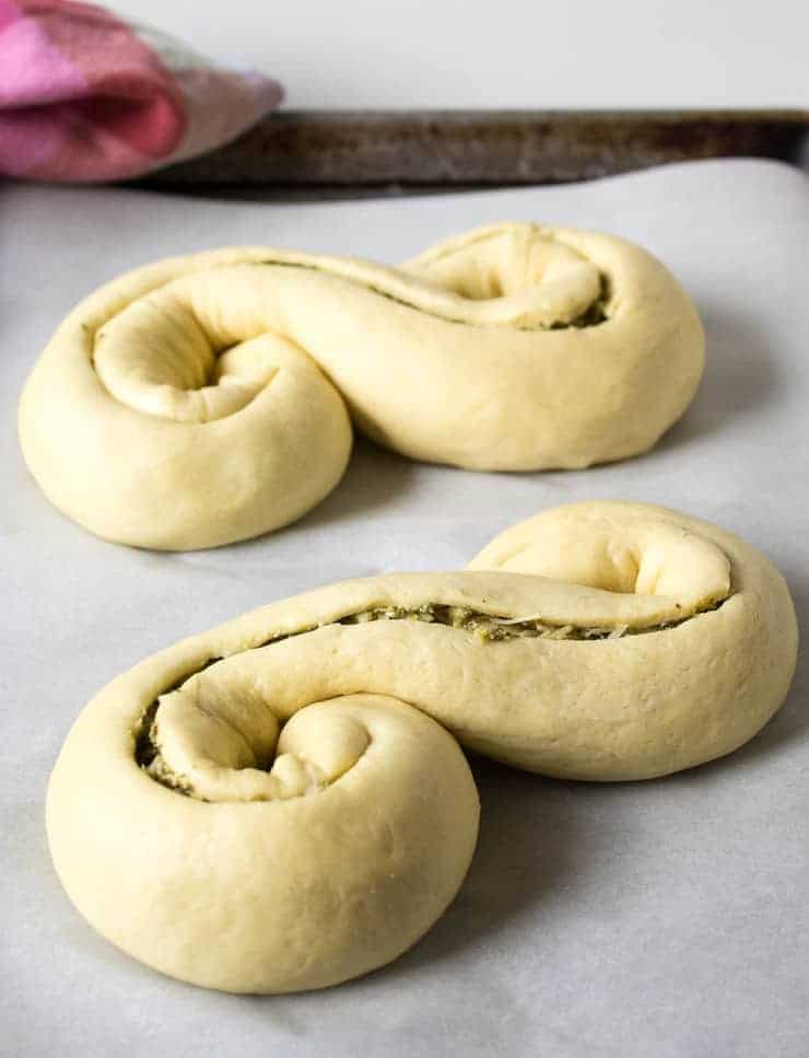 Bread dough shaped like an s and slit on the top of each loaf. 