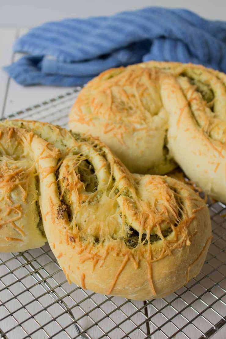 Loaves of bread on a baking rack with a blue towel behind the loaves. 