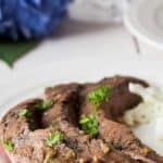 Slices of cooked flank steak on a white plate.