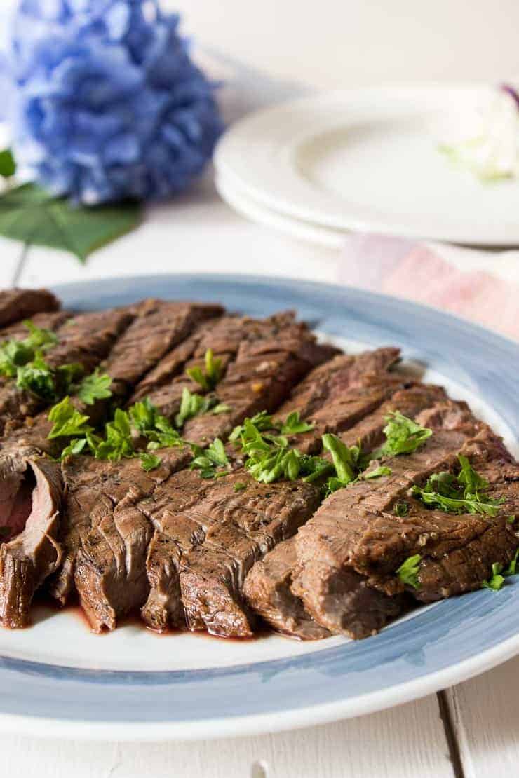 Slice flank steak on a blue and white plate. 