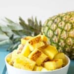 A white bowl filled with chunks of cooked pineapple.