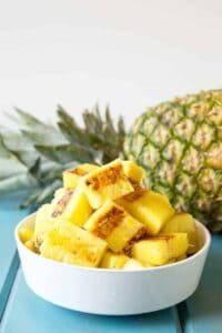 A white bowl filled with chunks of cooked pineapple.