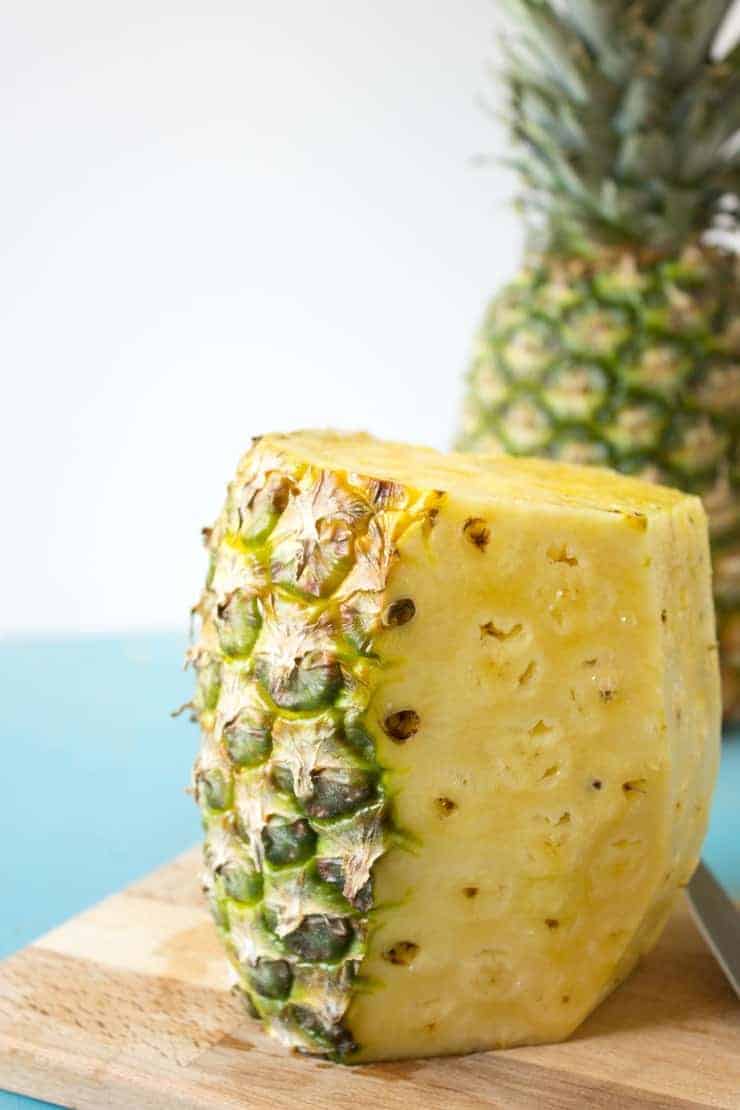 A pineapple with half the peel cut off.
