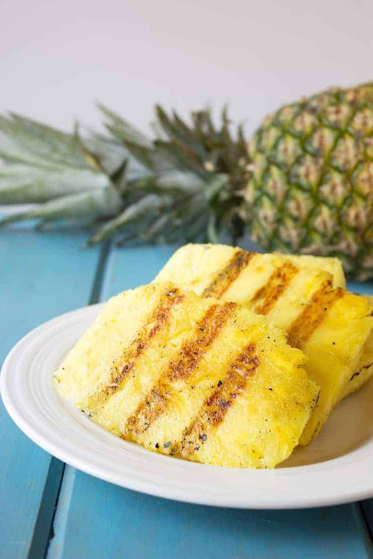 Slabs of grilled pineapple on a plate.