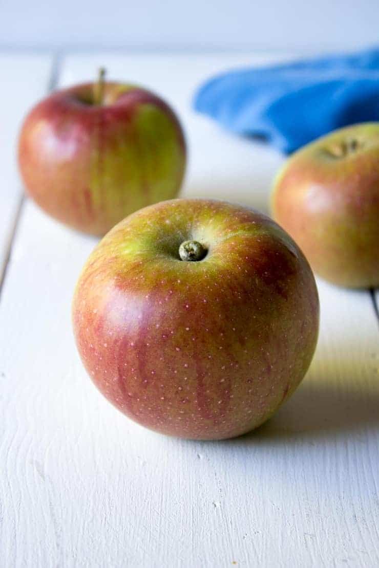 Fresh apples on a white board with a blue napkin in the background. 