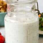 An old glass jar filled with blue cheese dressing and crumbled blue cheese in front of the jar.