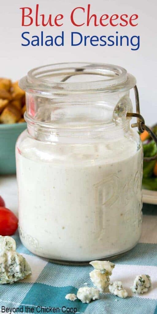 An old glass jar filled with blue cheese dressing and crumbled blue cheese in front of the jar.
