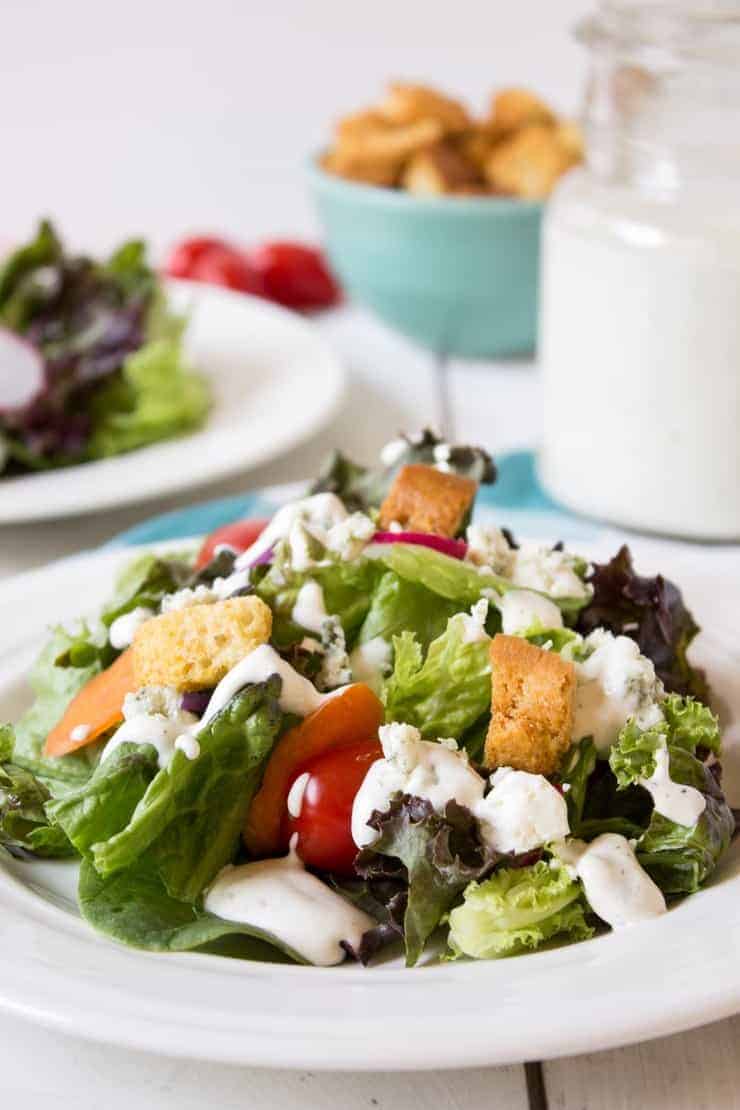 Blue cheese dressing drizzled on a green lettuce salad.