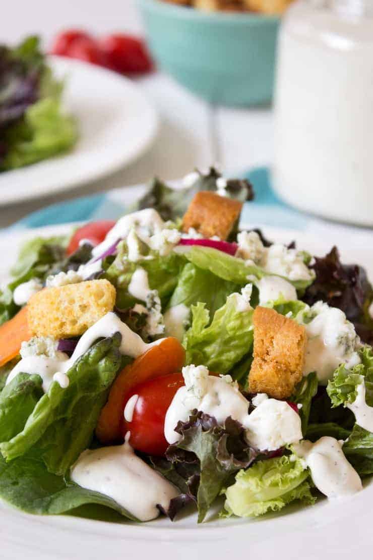 A lettuce salad with tomatoes, croutons and a white dressing. 