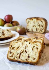 A loaf of apple babka sliced on a board.