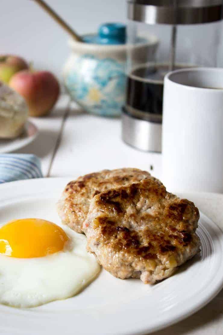 Two sausage patties and a fried egg on a white plate. 