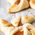 A breakfast pastry filled with apricot jam on a baking sheet.