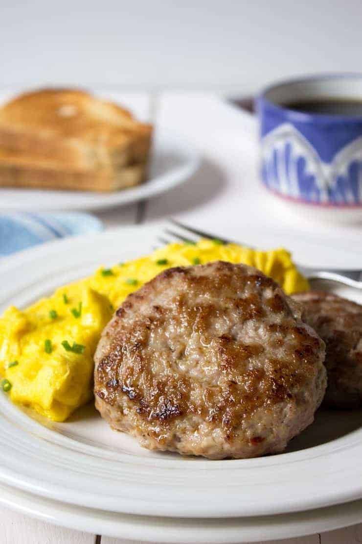 Sausage patties and scrambled eggs on a white plate. 