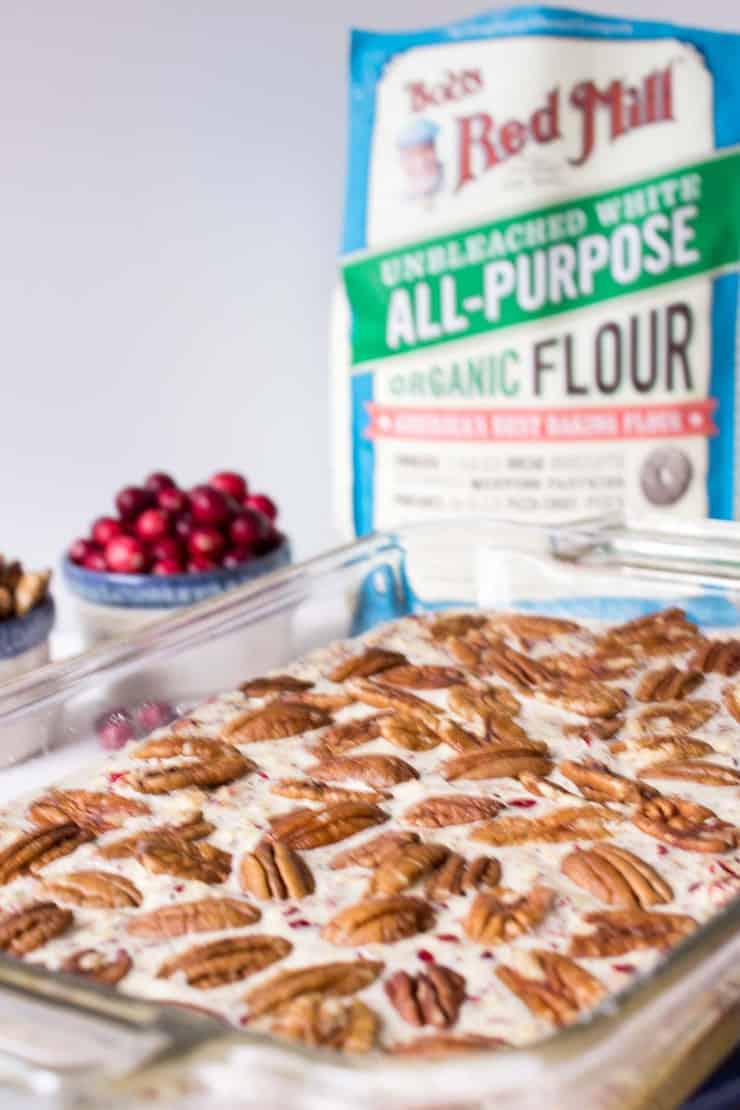 A baking dish filled with an unbaked dessert with pecans.