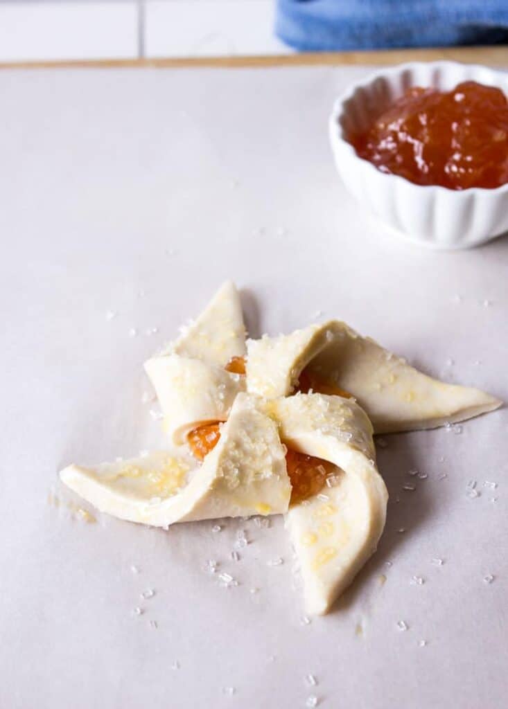 An unbaked pastry with jam and a spinkling of sugar.