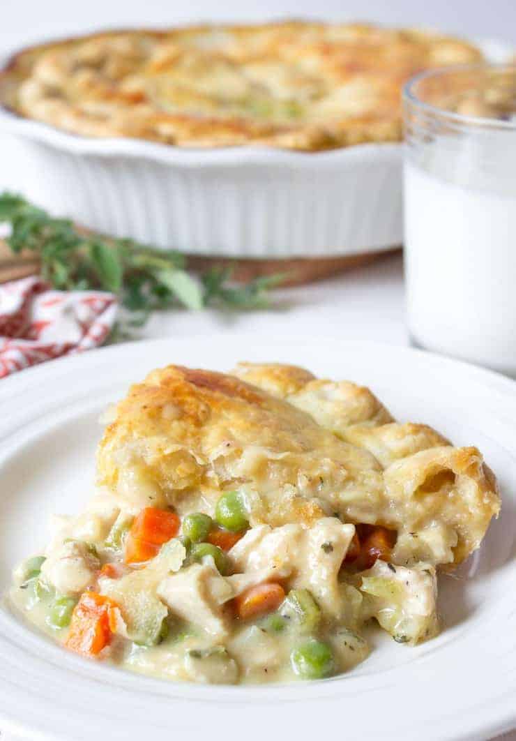 A serving of chicken pot pie with a crust on a white plate.