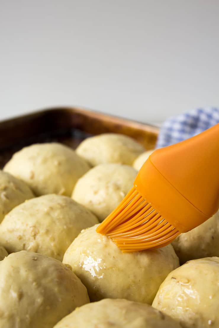 Brushing butter on uncooked rolls. 