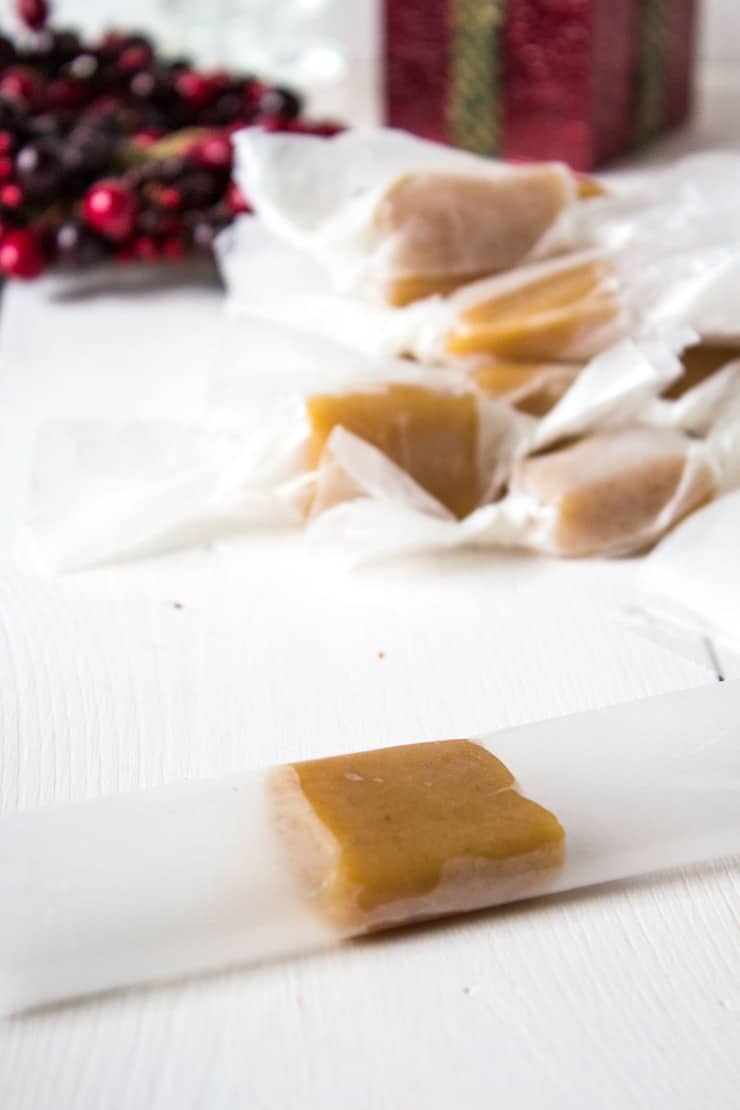 A piece of caramel being folded up into a piece of waxed paper.