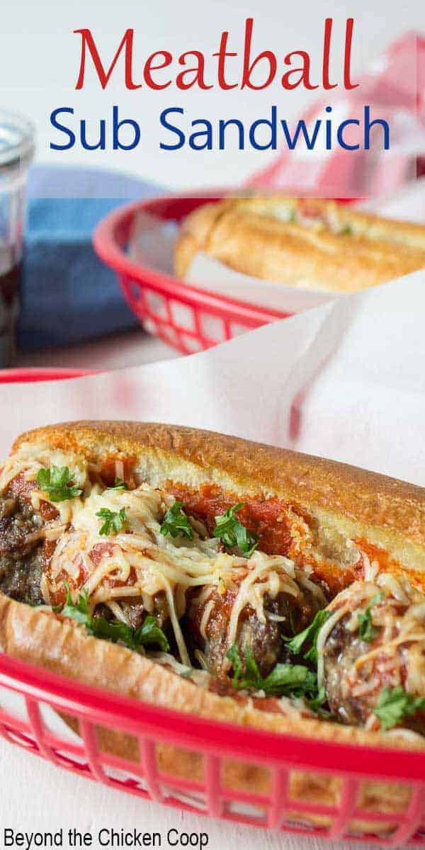A hoagie roll filled with meatballs, sauce and cheese in a red basket.