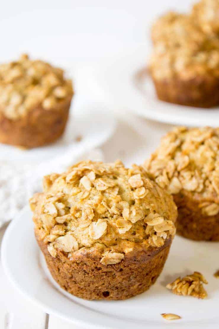 White plates and white napkins filled with crumbly oatmeal muffins. 