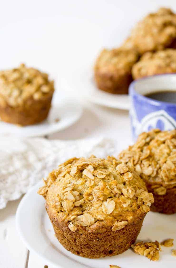 Banana muffins topped with oats sitting on a white plate. 