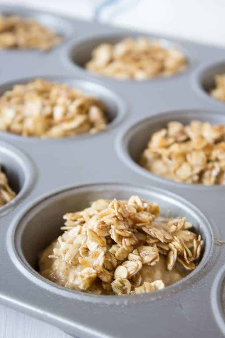 Muffin tin filled with batter topped with oatmeal. 