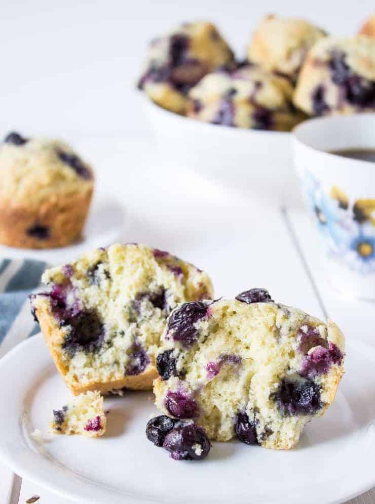Homemade blueberry muffins split in half and served on a plate.
