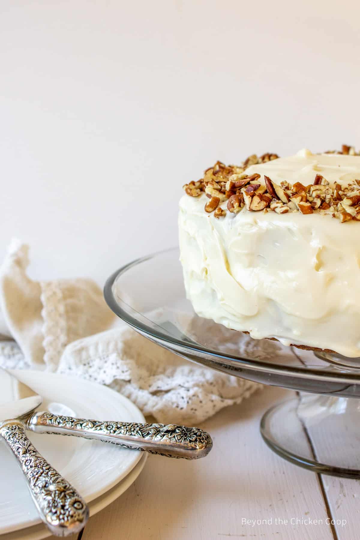 A layered carrot cake topped with cream cheese frosting and pecans. 