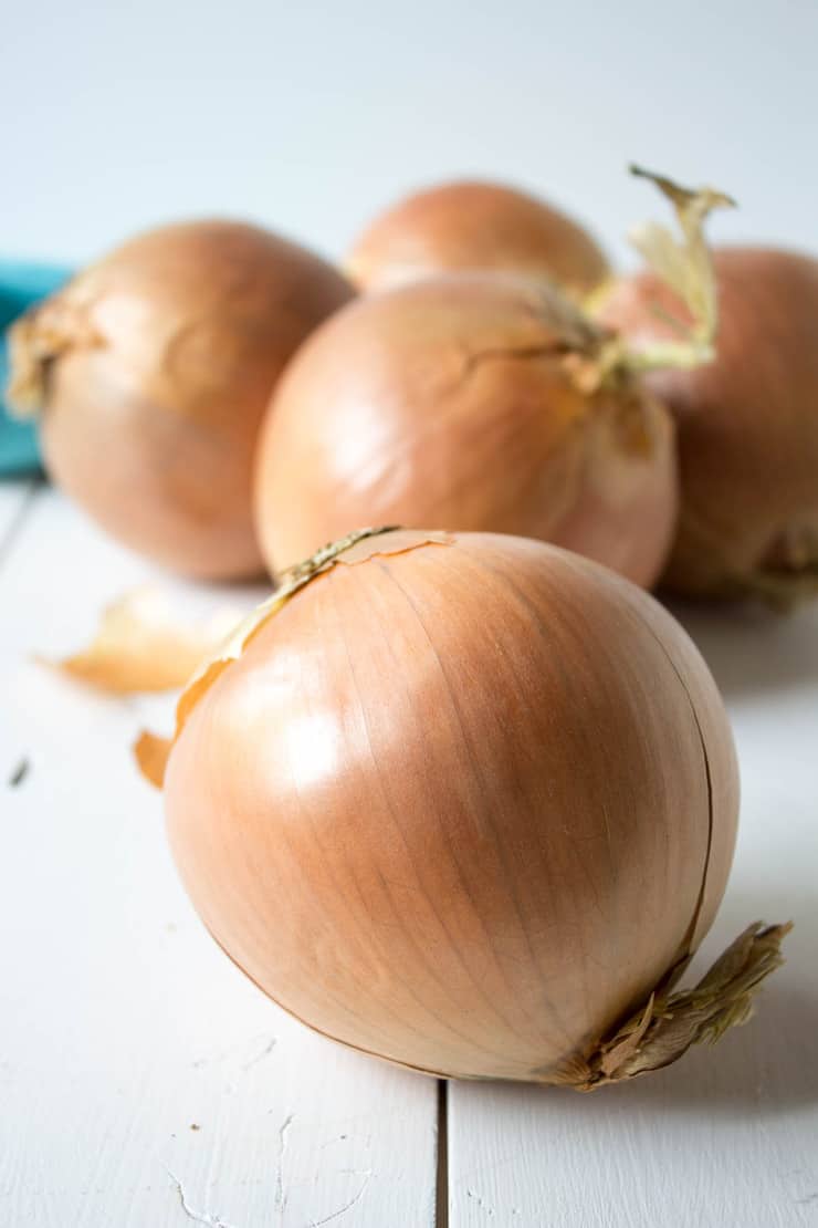 Yellow onions on a white board.