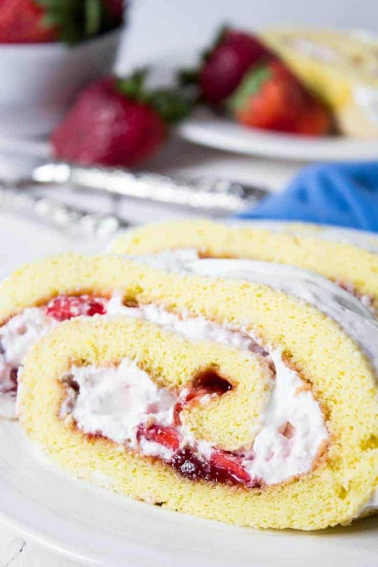 A slice of strawberry roll cake filled with fresh strawberries and whipped cream