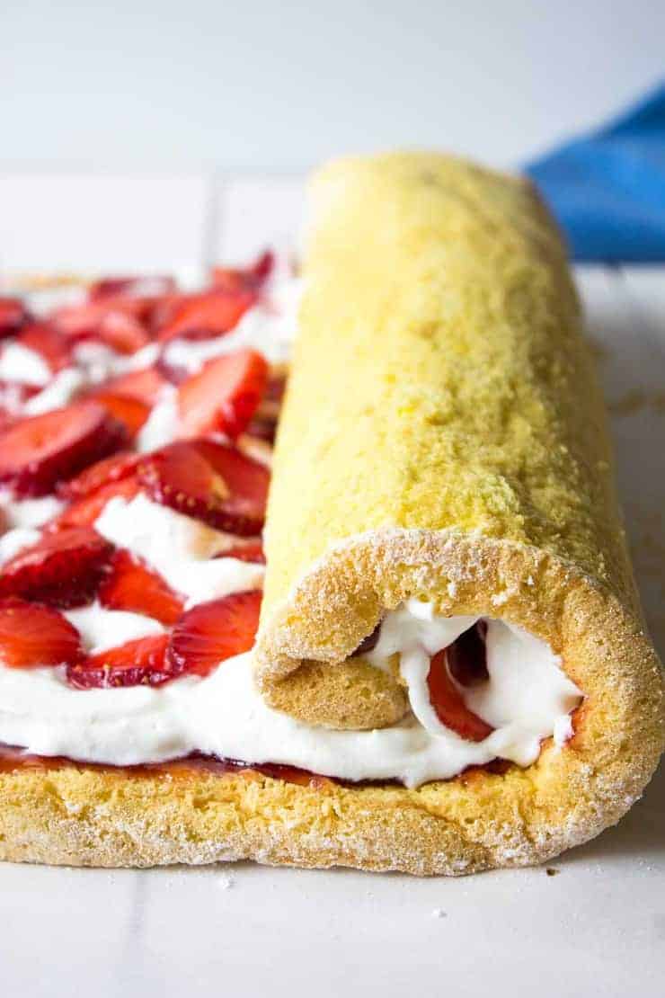 Rolling up a yellow cake filled with fresh strawberries and whipped cream!