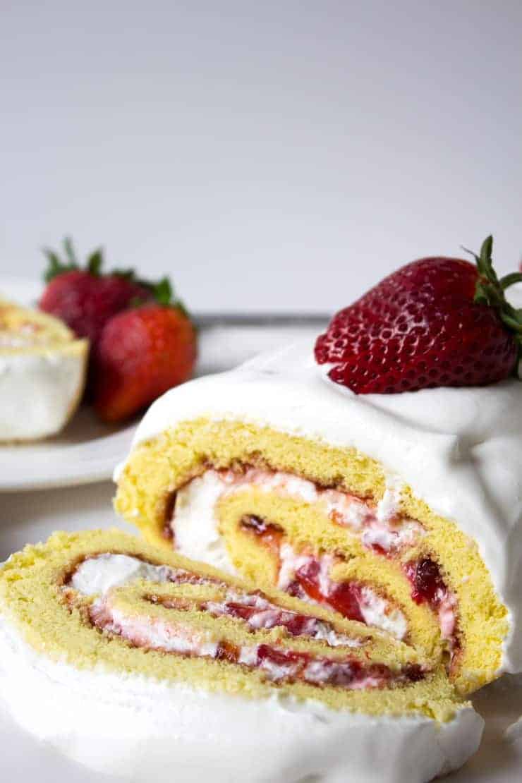 Fresh strawberry filled cake sliced and topped with fresh strawberries.