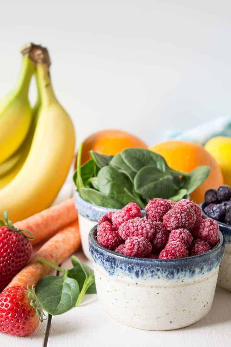 Bananas, raspberries, spinach, carrots and other fruits displayed on a white board.
