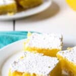 Three lemon bars topped with powdered sugar on a white plate.