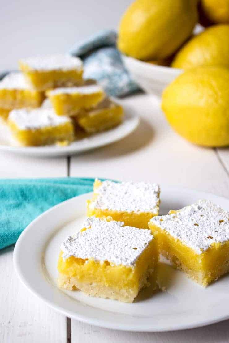 Three lemon bars topped with powdered sugar on a plate. 