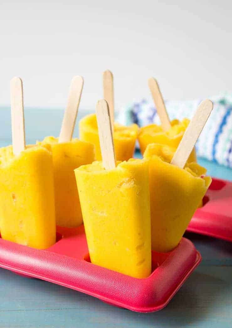 Yellow popsicles in a red tray.