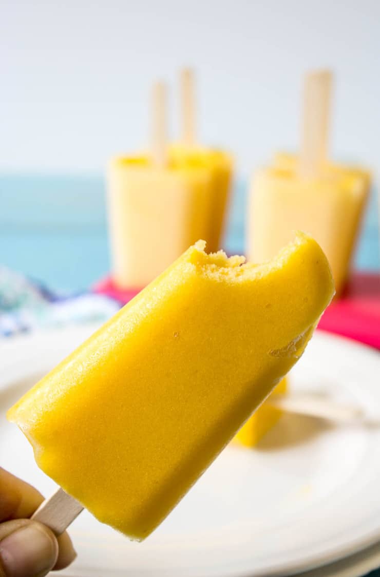 Mango Peach Popsicle with a bite out of it.