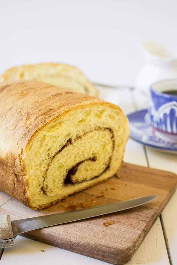 Cinnamon Swirl Bread sitting on a wooden cutting board.